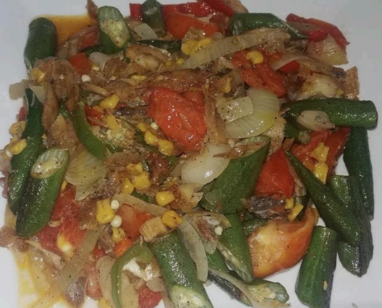 Colorful stir-fried vegetables with okra, tomatoes, onions, and corn on a white plate