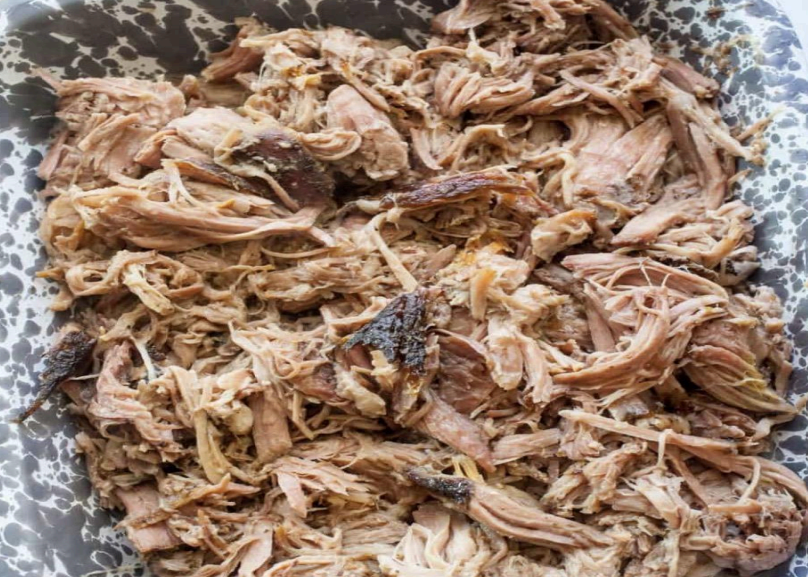 Shredded cooked meat piled in a speckled bowl, with browned crispy bits throughout