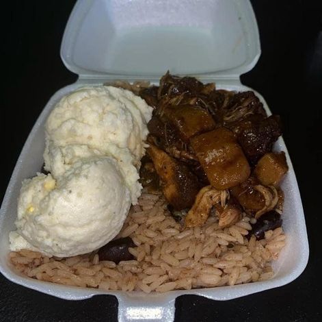Takeout container with rice, roasted meat, and two scoops of mashed potatoes