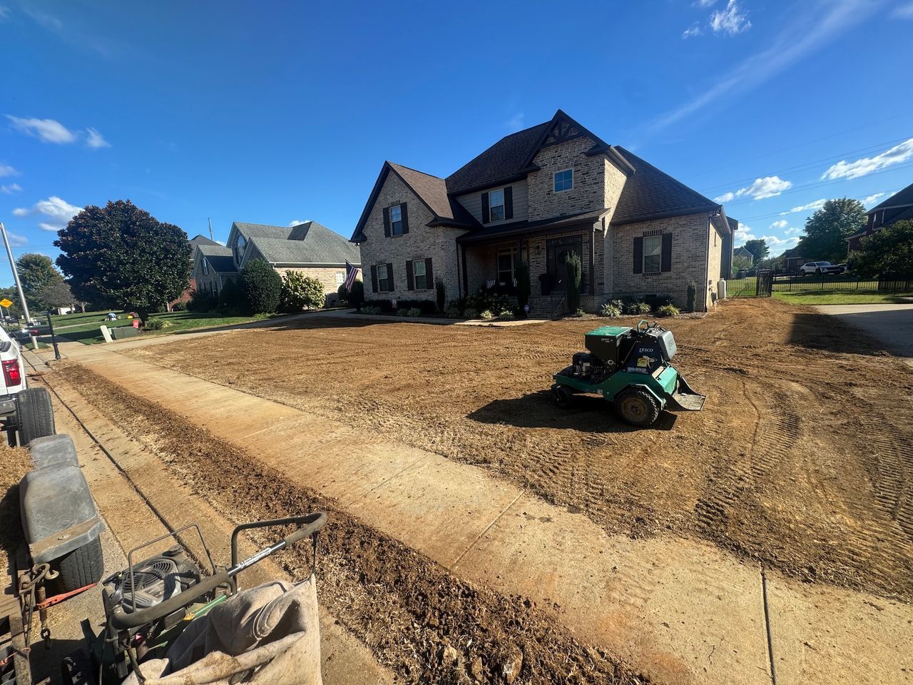 New house under construction with a dirt lot and a green skid steer in front