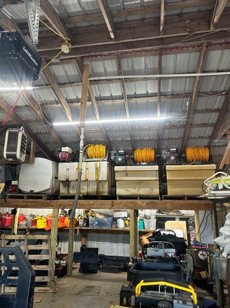 Warehouse interior with shelves of equipment and tools under a high metal roof