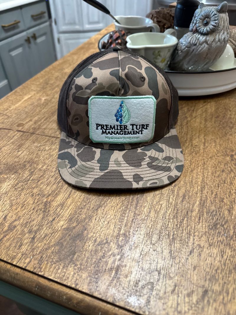 Camouflage baseball cap with a turquoise patch on a wooden table in a kitchen