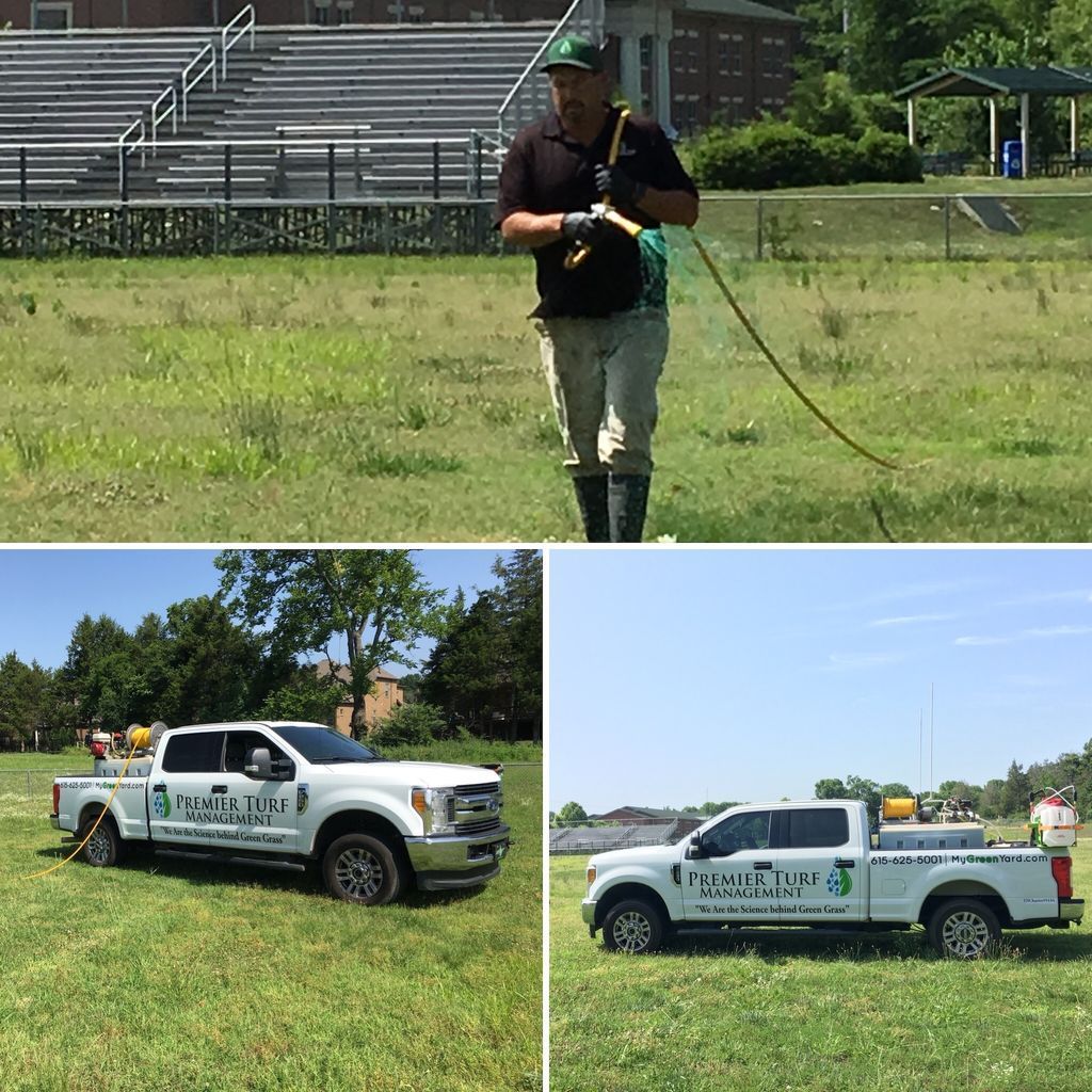 Worker using surveying equipment in a grassy field; two white utility trucks parked nearby.