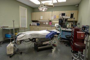 Operating room with patient on table, medical equipment, and cabinets.