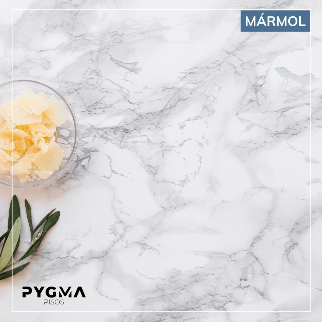 Muestra de azulejo con estampado de mármol, veteado blanco y gris, marcado con las palabras “MÁRMOL” y “PYGMA”.