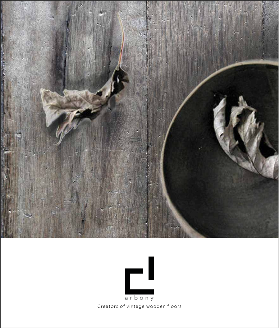 Tablero de mesa de madera gris con hojas secas y un cuenco negro, además de un pequeño logotipo en la parte inferior.