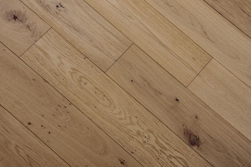 Suelo de tablones de roble claro colocados en diagonal, con vetas y nudos visibles.