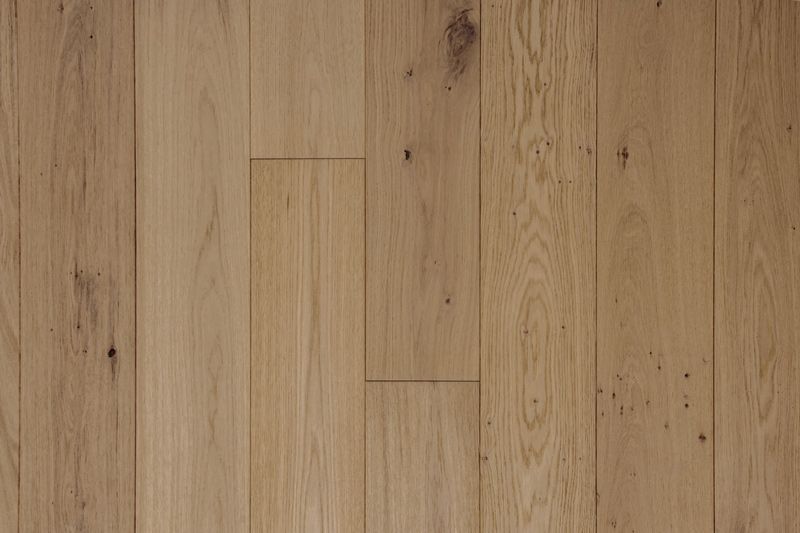 Suelo de madera de roble claro con juntas verticales estrechas entre las tablas y nudos visibles.