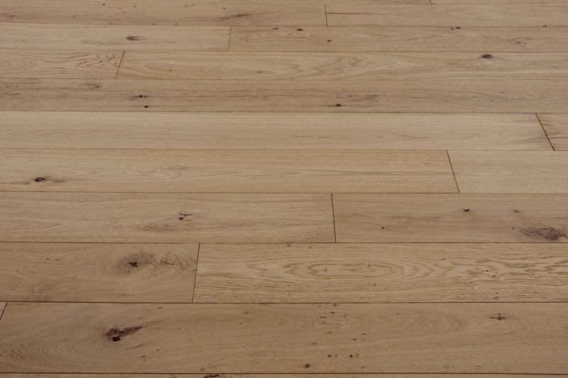 Suelo de madera de color claro con vetas y nudos naturales.