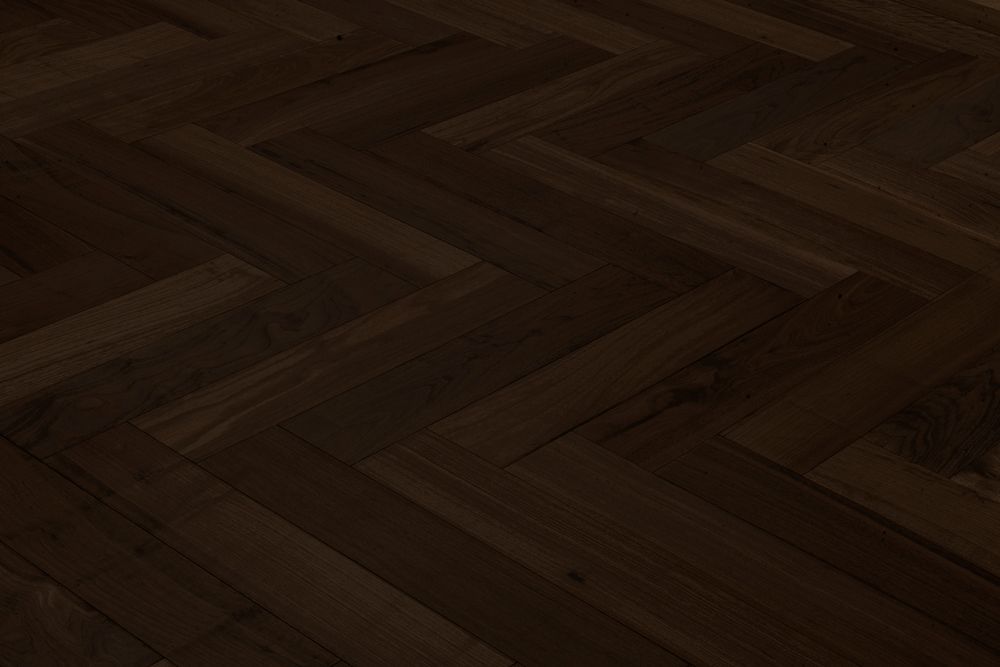 Suelo de tablones de madera oscura en espiga con poca luz.