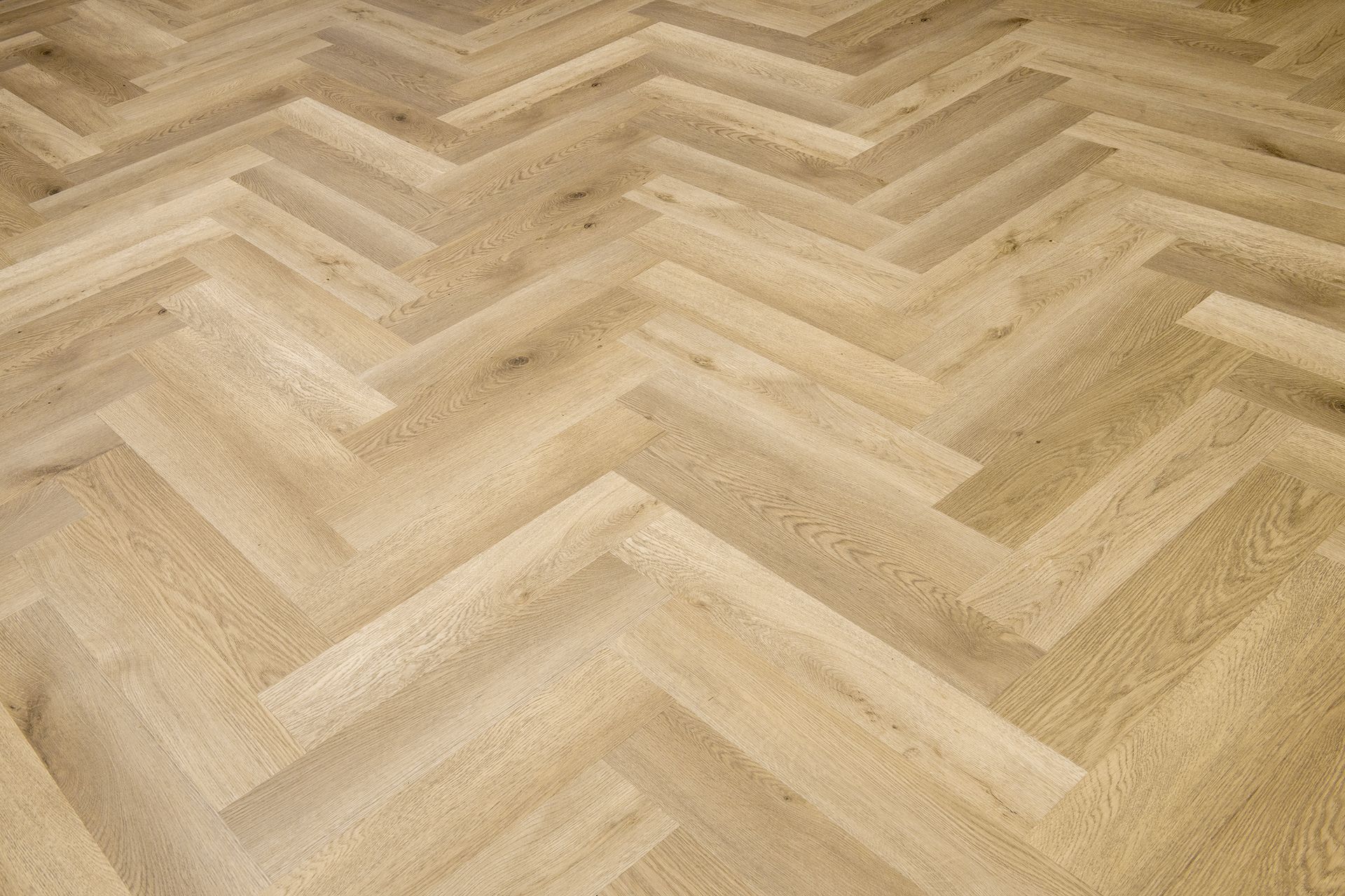 Suelo de parquet de madera clara en espiga con acabado natural y pálido.