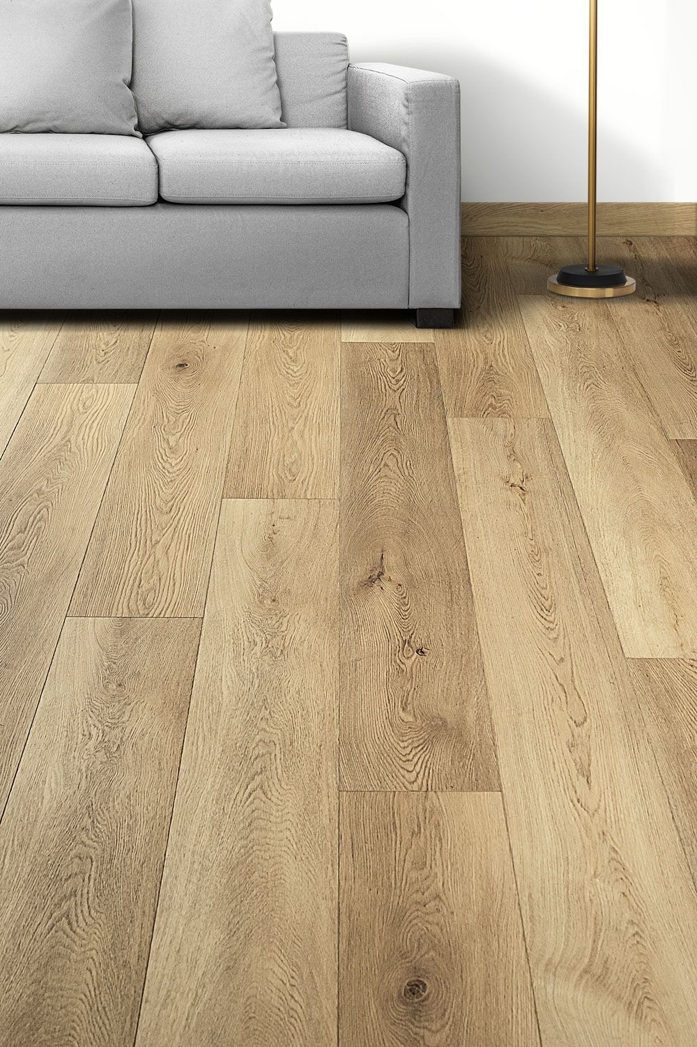 Suelo de madera con un sofá gris y una lámpara de pie en un salón luminoso.
