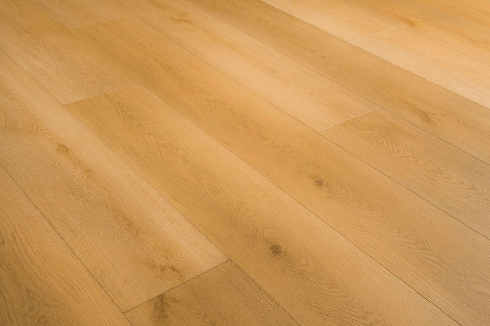 Suelo de madera de color claro con juntas diagonales entre tablones y un sutil veteado.