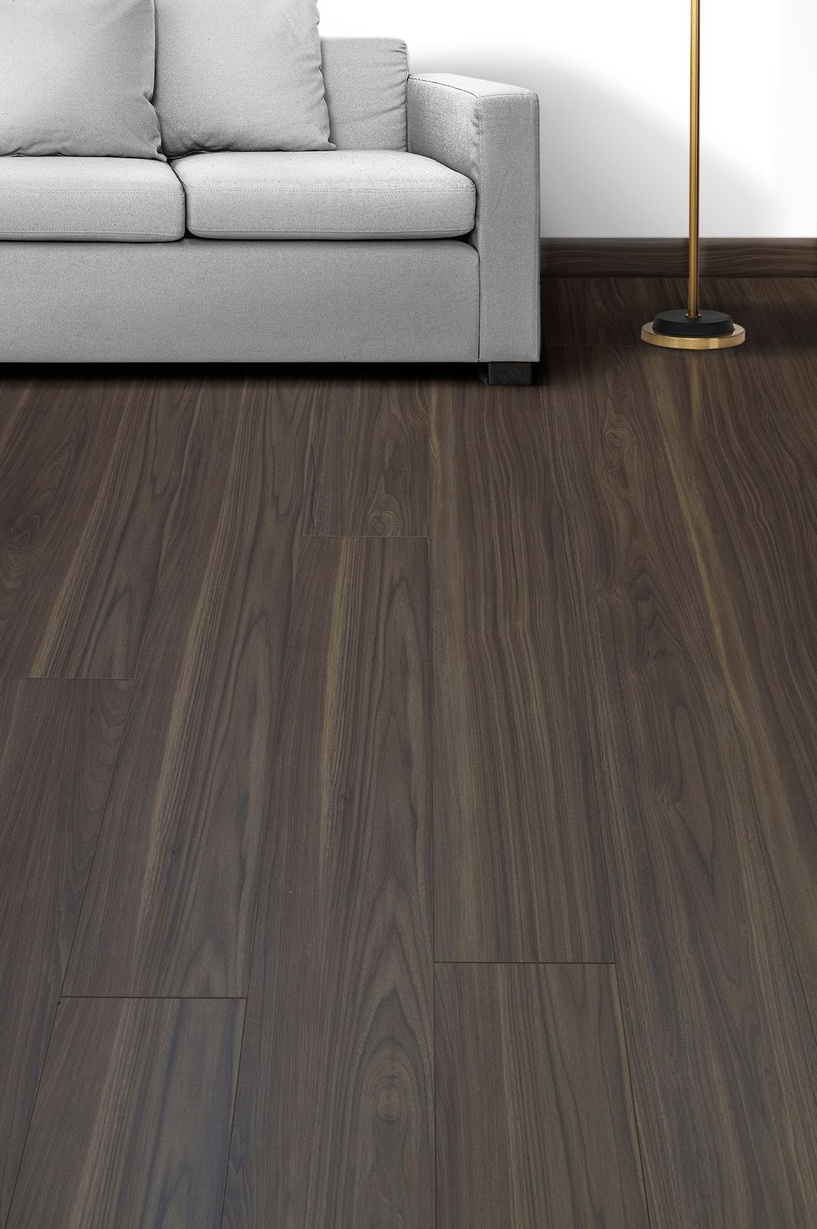 Sala de estar moderna con sofá gris, suelo de madera oscura y lámpara de pie de latón.