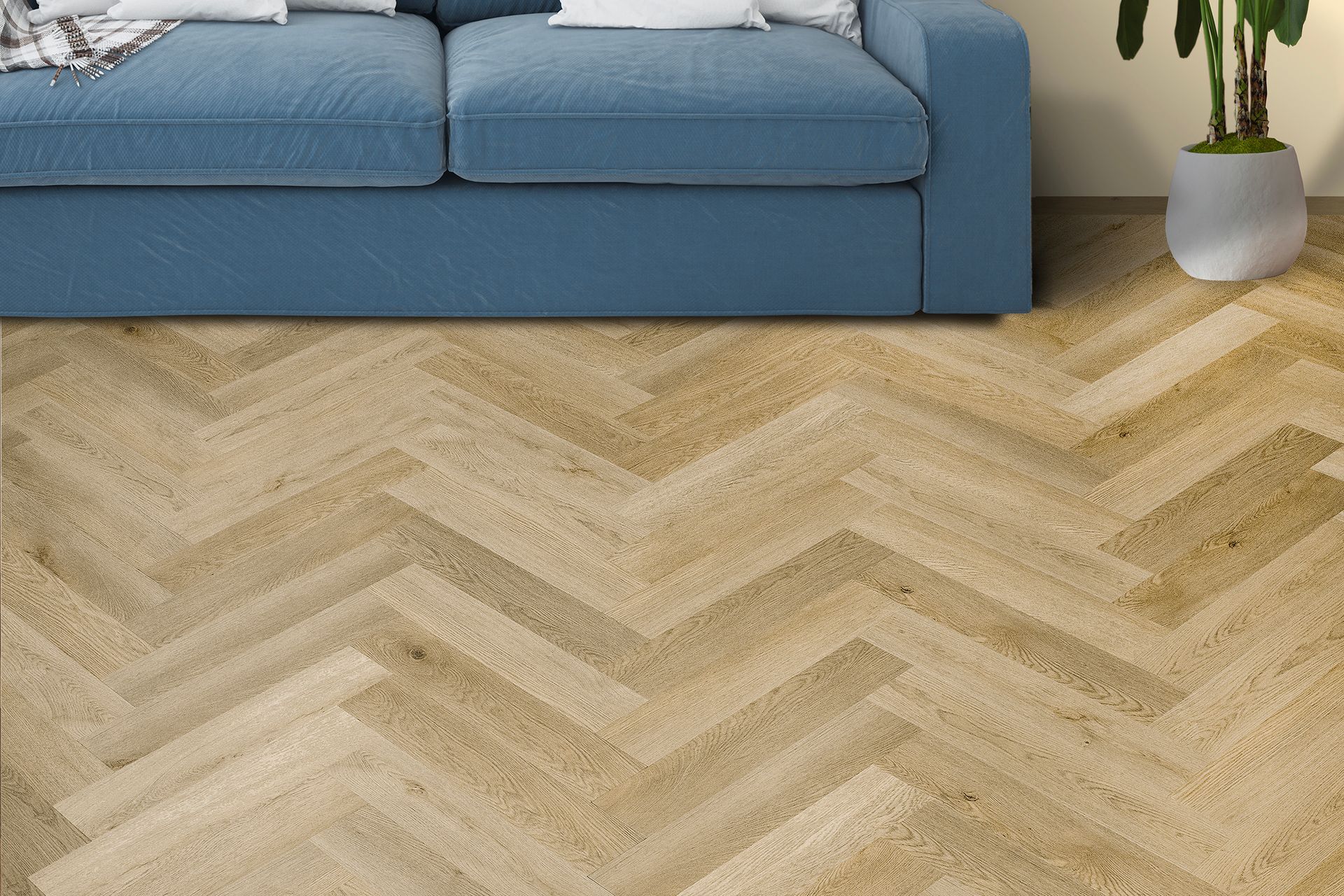 Sofá azul sobre una alfombra beige con estampado de espiga en una sala de estar luminosa.