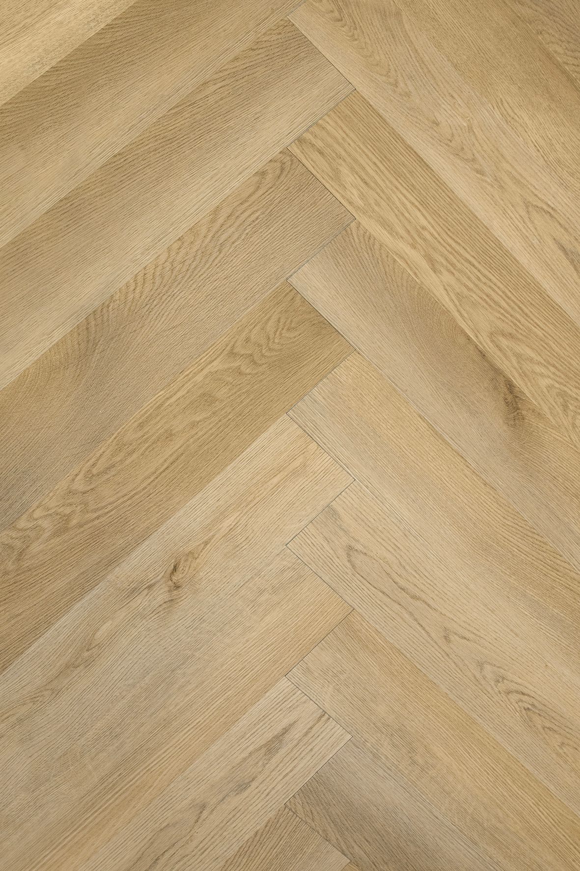 Suelo de madera clara con diseño de espiga en tonos tostados y beige.