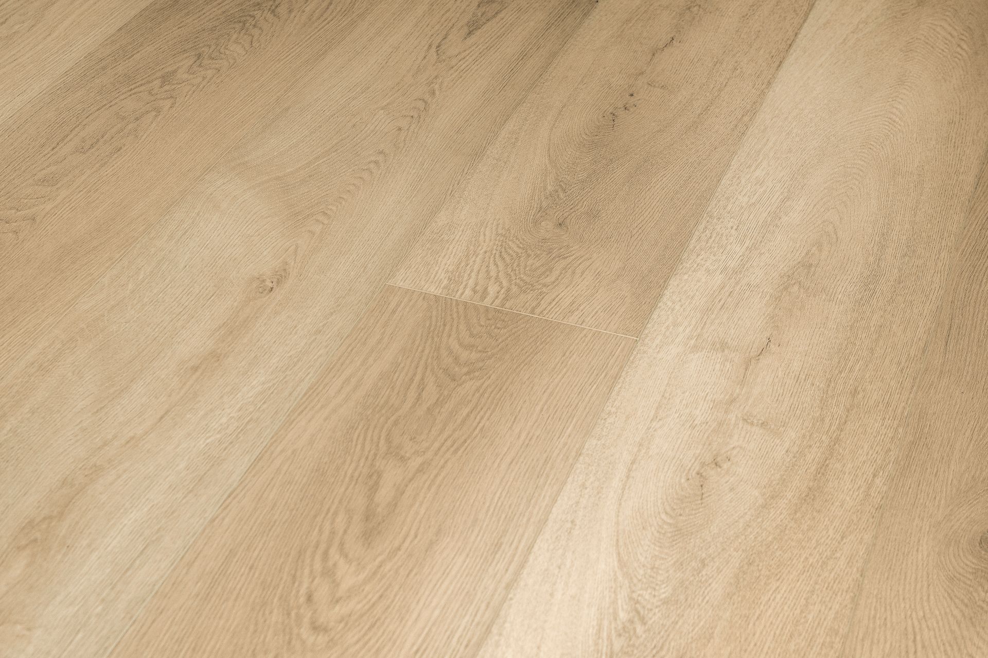 Primer plano de un suelo de madera clara con vetas y un patrón de tablones diagonales.