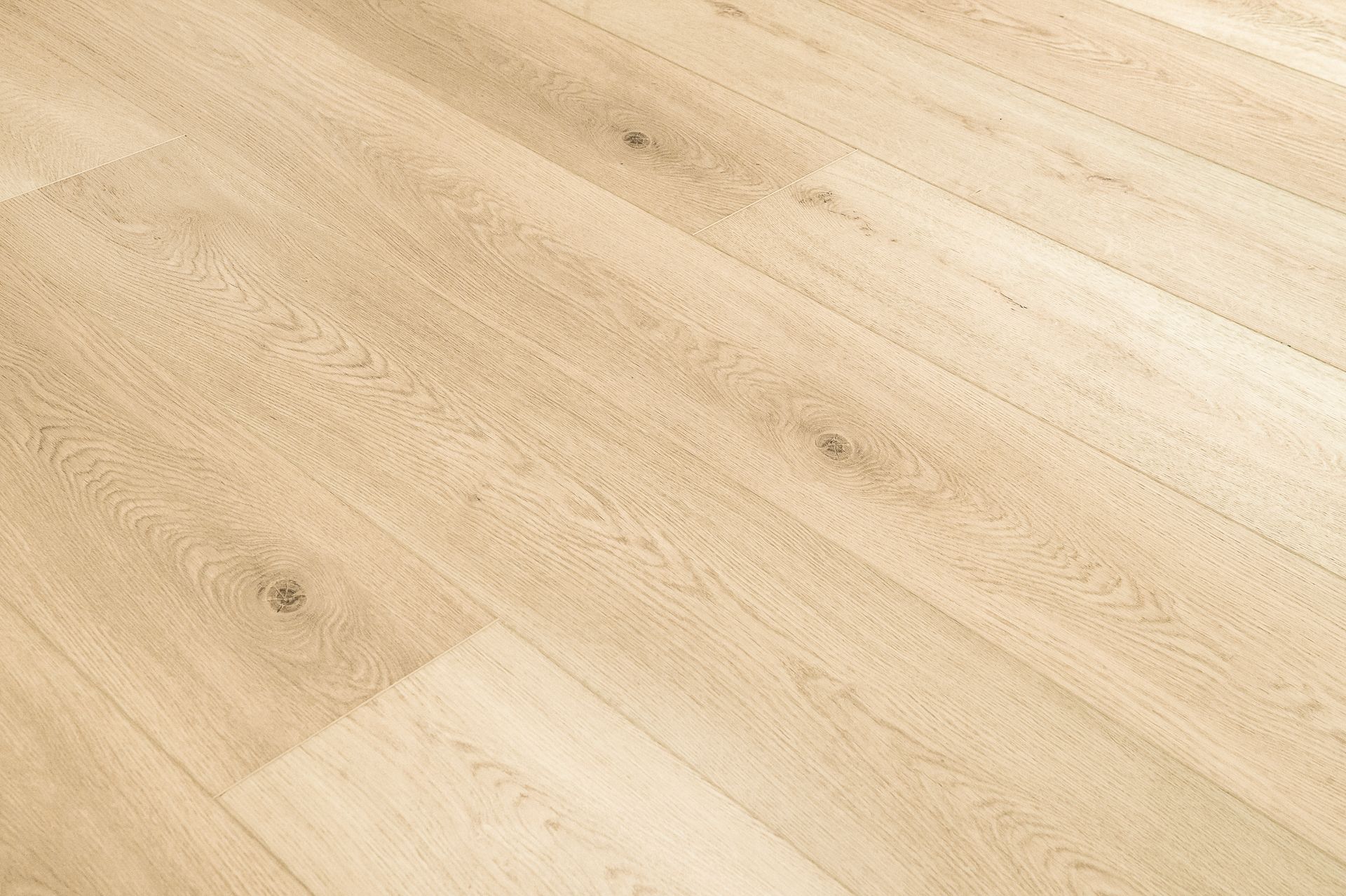 Suelo de madera de color claro con vetas sutiles y algunas pequeñas marcas.