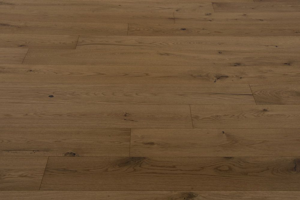 Primer plano de un suelo de madera de color marrón claro con vetas y juntas de tablones visibles.