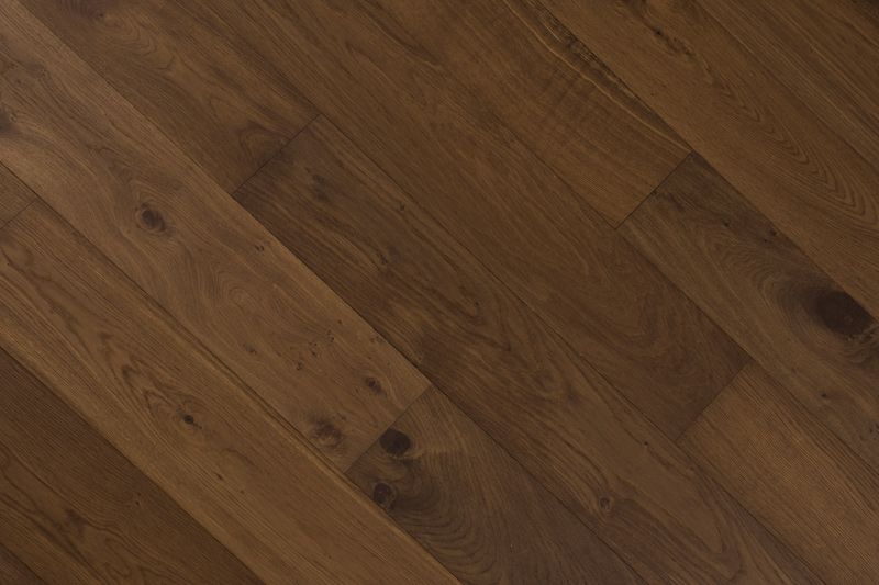 Tablones de madera marrón colocados en diagonal, dejando ver la veta y los nudos de la madera.