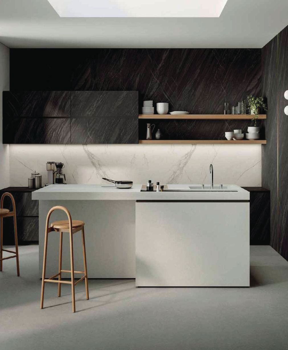 Cocina moderna minimalista con armarios de madera oscura, isla blanca y taburete de cobre.