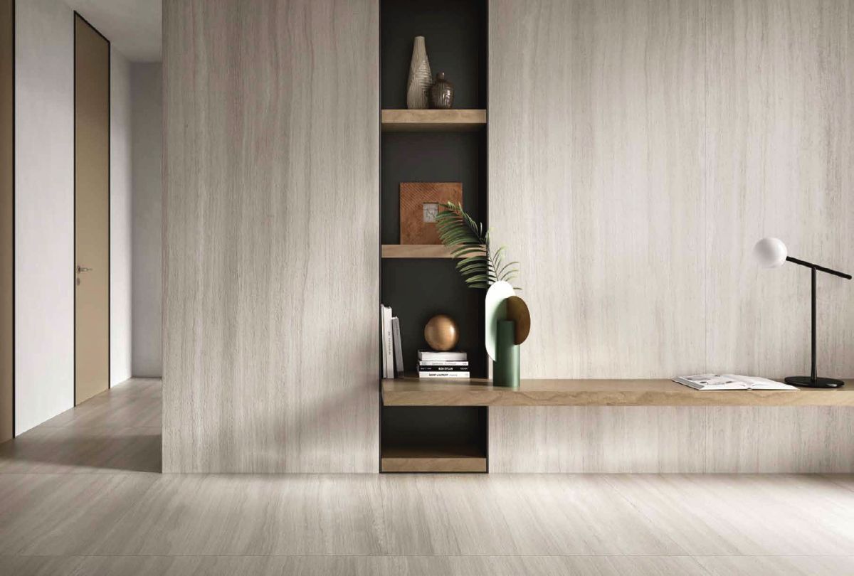 Interior minimalista con estanterías empotradas, suelos de madera clara, un asiento bajo tipo plataforma y una lámpara de escritorio.