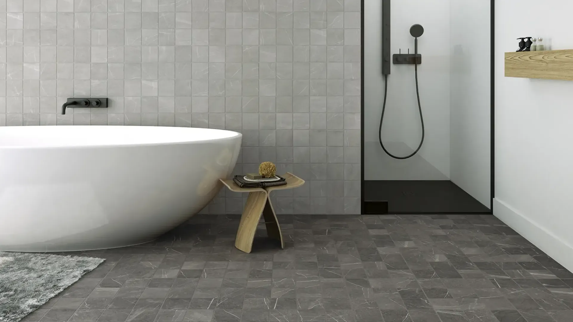 Baño moderno con bañera independiente, ducha a ras de suelo, suelo de baldosas grises y pequeño taburete de madera.