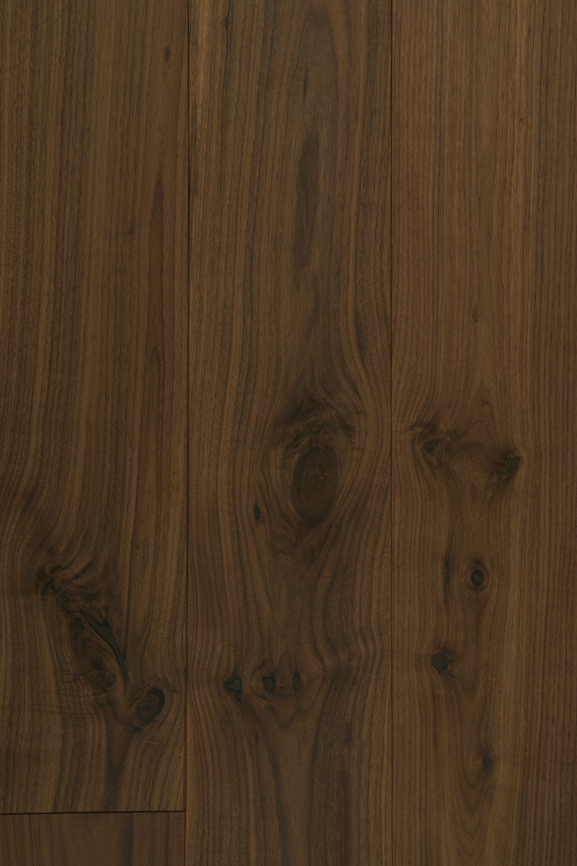 Primer plano de una superficie de madera de color marrón oscuro con vetas, nudos y tablones verticales.