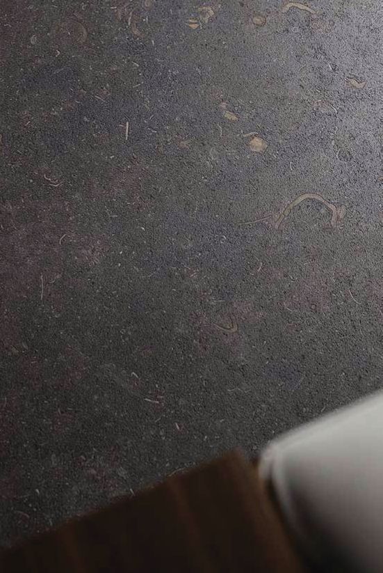 Primer plano de una superficie texturizada de color gris oscuro con un pequeño objeto blanco en el borde inferior derecho.