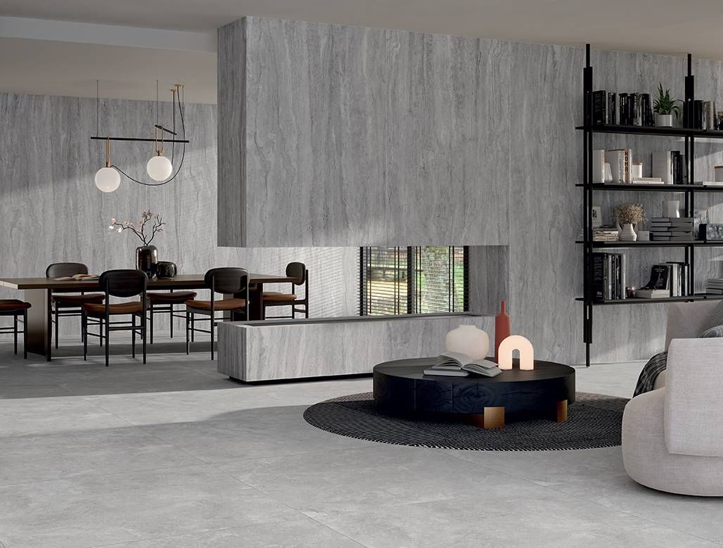 Salón-comedor moderno de concepto abierto con decoración neutra, estanterías negras y una mesa de centro redonda.