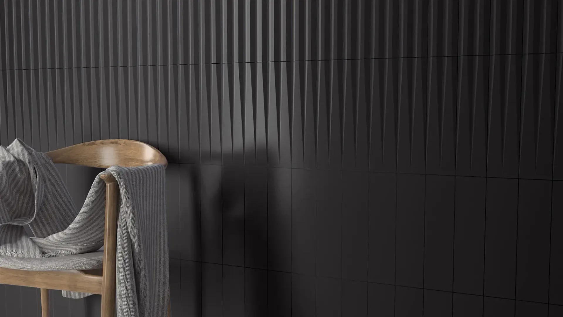 Una silla de madera cubierta con una manta gris, situada junto a una pared oscura y acanalada.