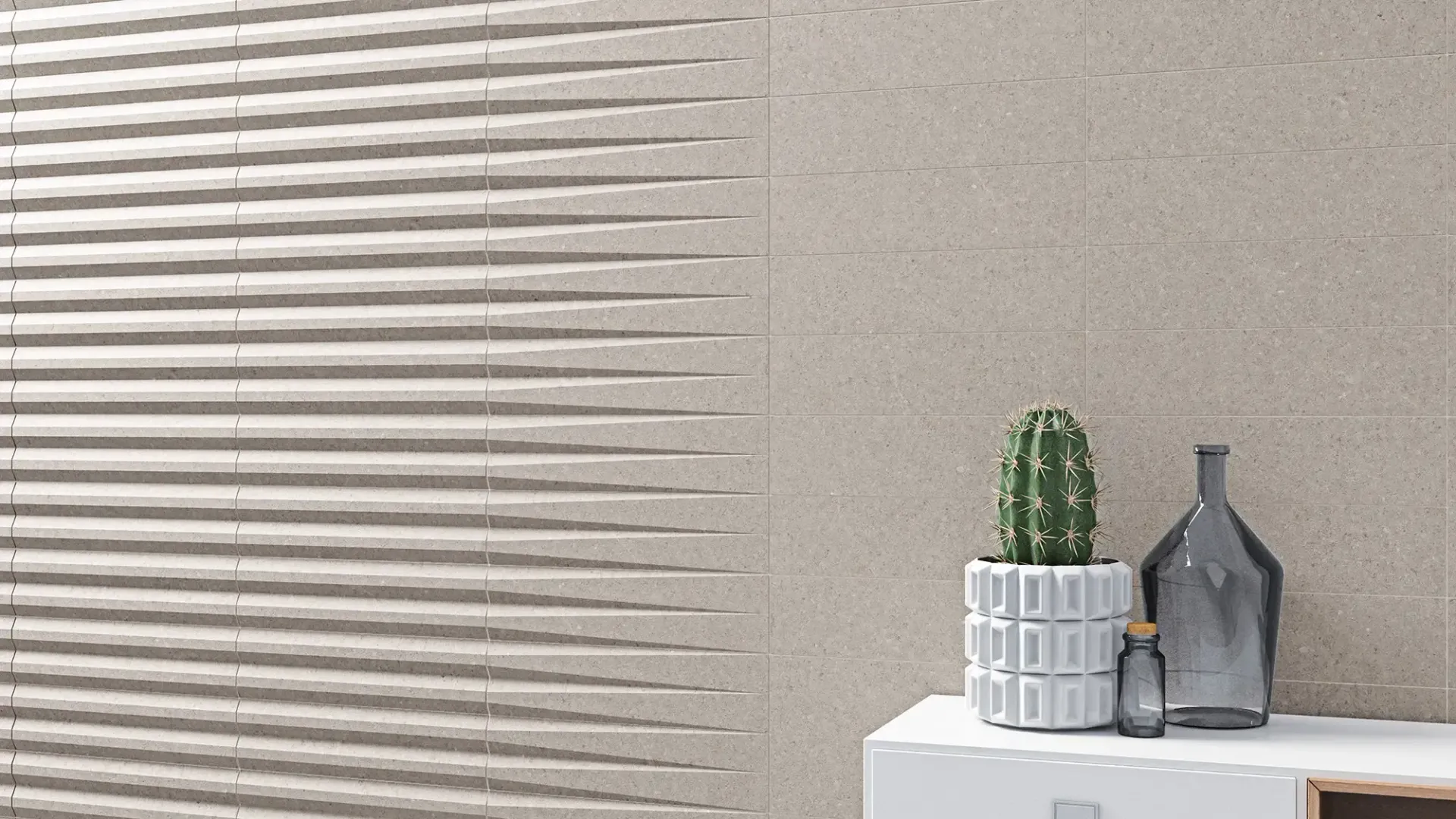 Pared de color beige con textura, persianas horizontales, un pequeño cactus, un jarrón gris y decoración blanca sobre un estante.