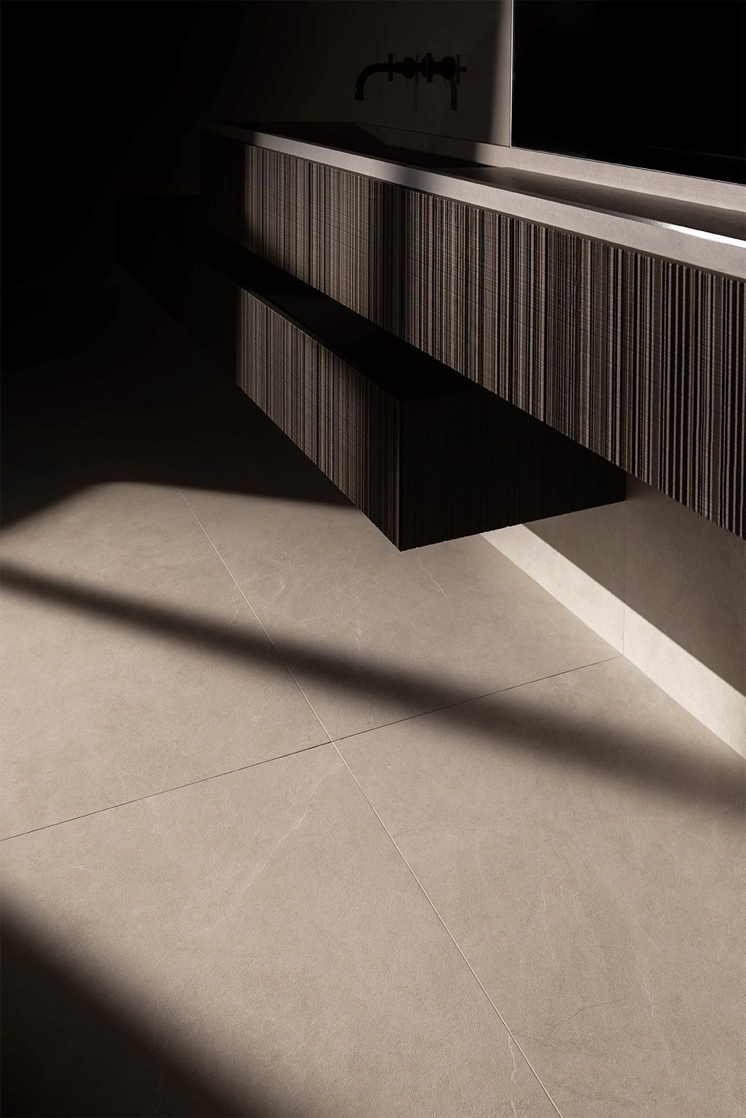 Un suelo de hormigón bañado por el sol junto a un banco acanalado en blanco y negro en un interior moderno.