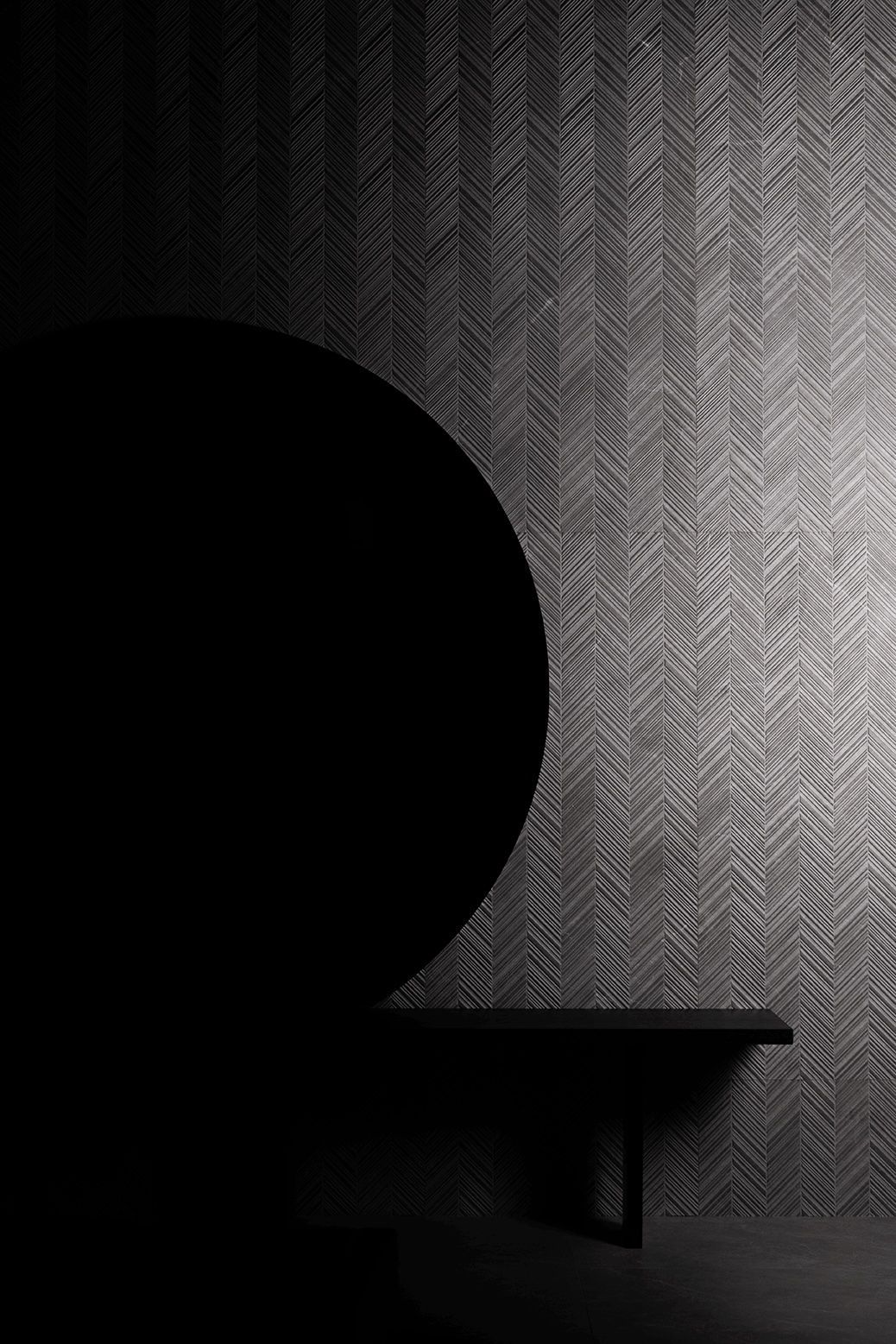 Habitación oscura con papel pintado estampado, una silla circular negra y una mesita en penumbra.