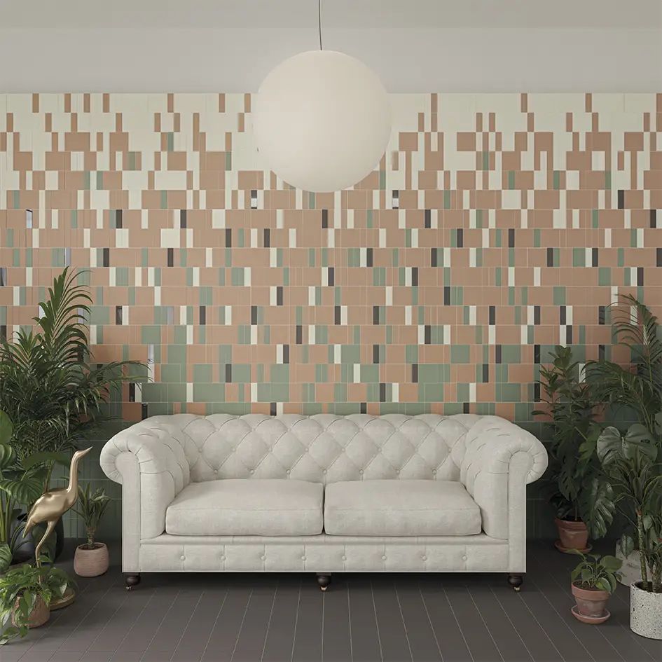 Sofá blanco capitoné contra una pared de azulejos estampados con plantas en macetas y una lámpara colgante esférica.