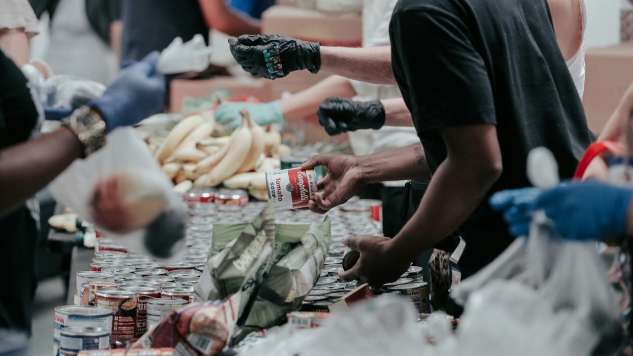 A group of people are standing around a table filled with food.