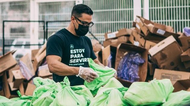 A man wearing a mask and gloves is standing in front of a pile of boxes.