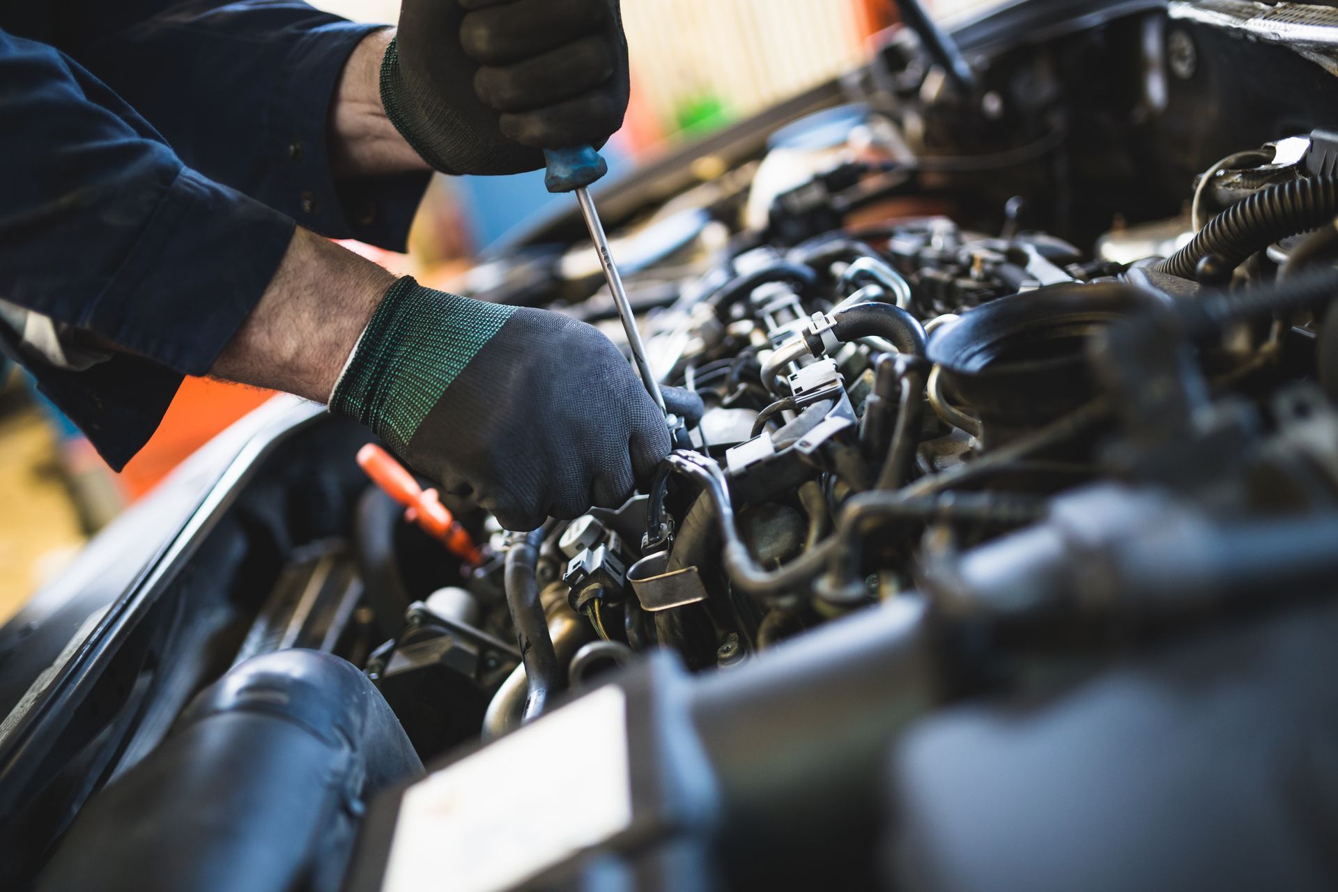 Mechanic using a screwdriver to repair a car engine in a workshop