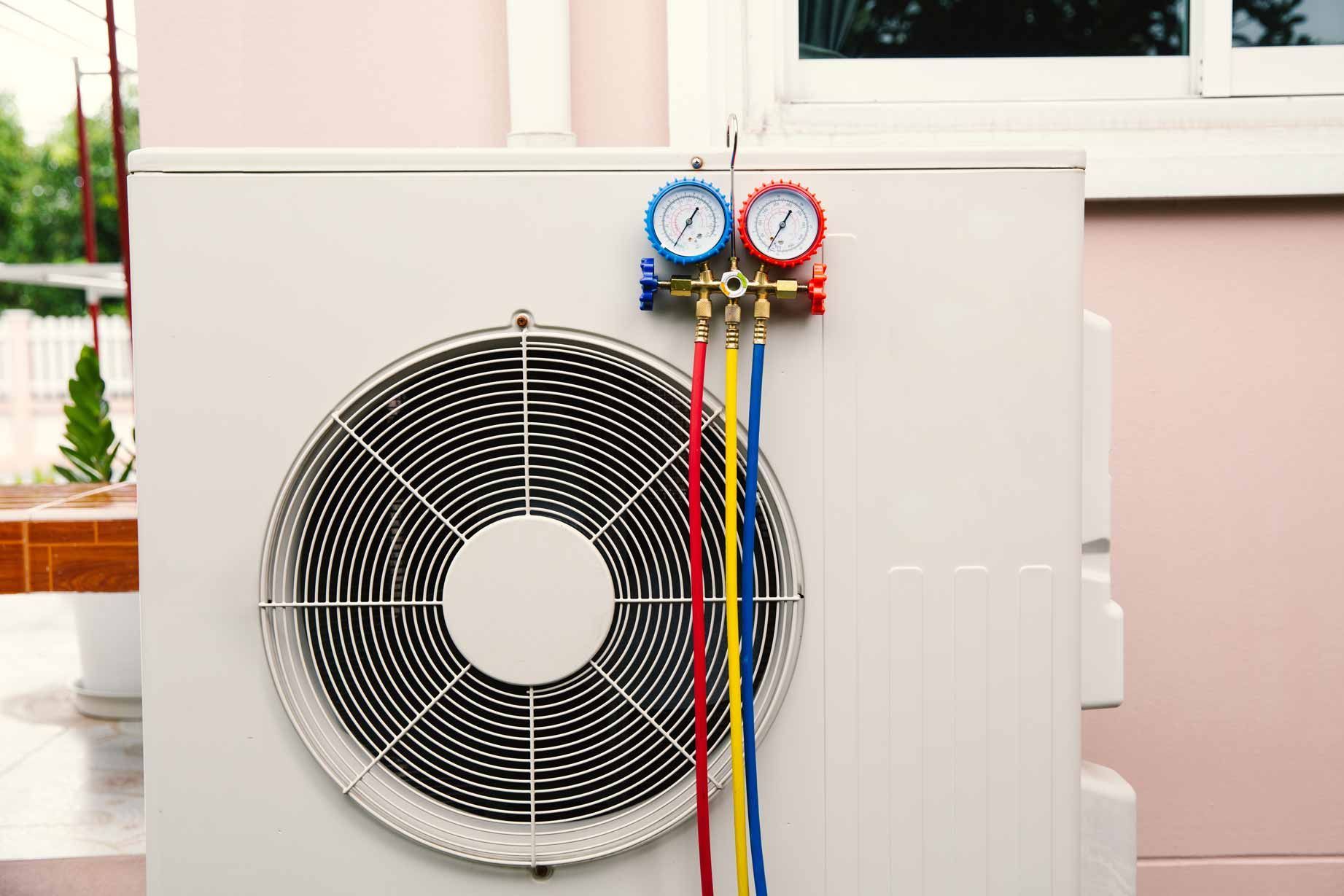 Outdoor air conditioner unit with blue and red gauges and colored hoses attached