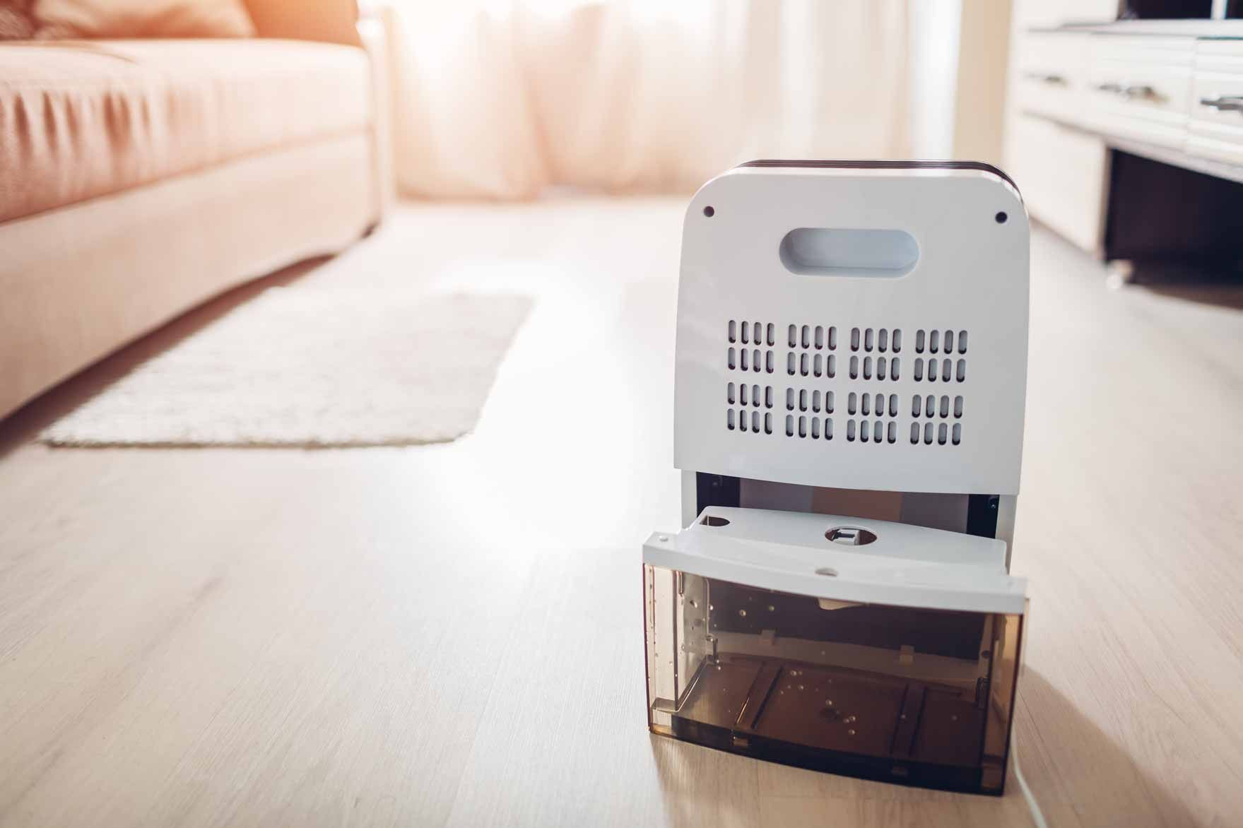 White robot vacuum docked on a charger in a bright living room near a sofa