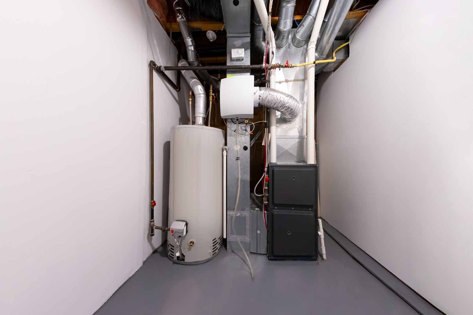 Mechanical room with ducts, pipes, and HVAC equipment in a narrow gray utility space