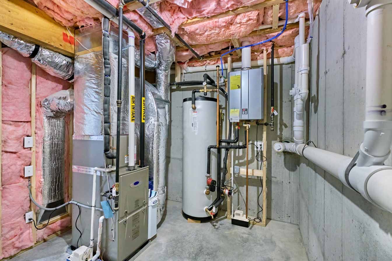 Basement utility room with water heater, furnace, ducts, and insulated pipes along concrete walls.