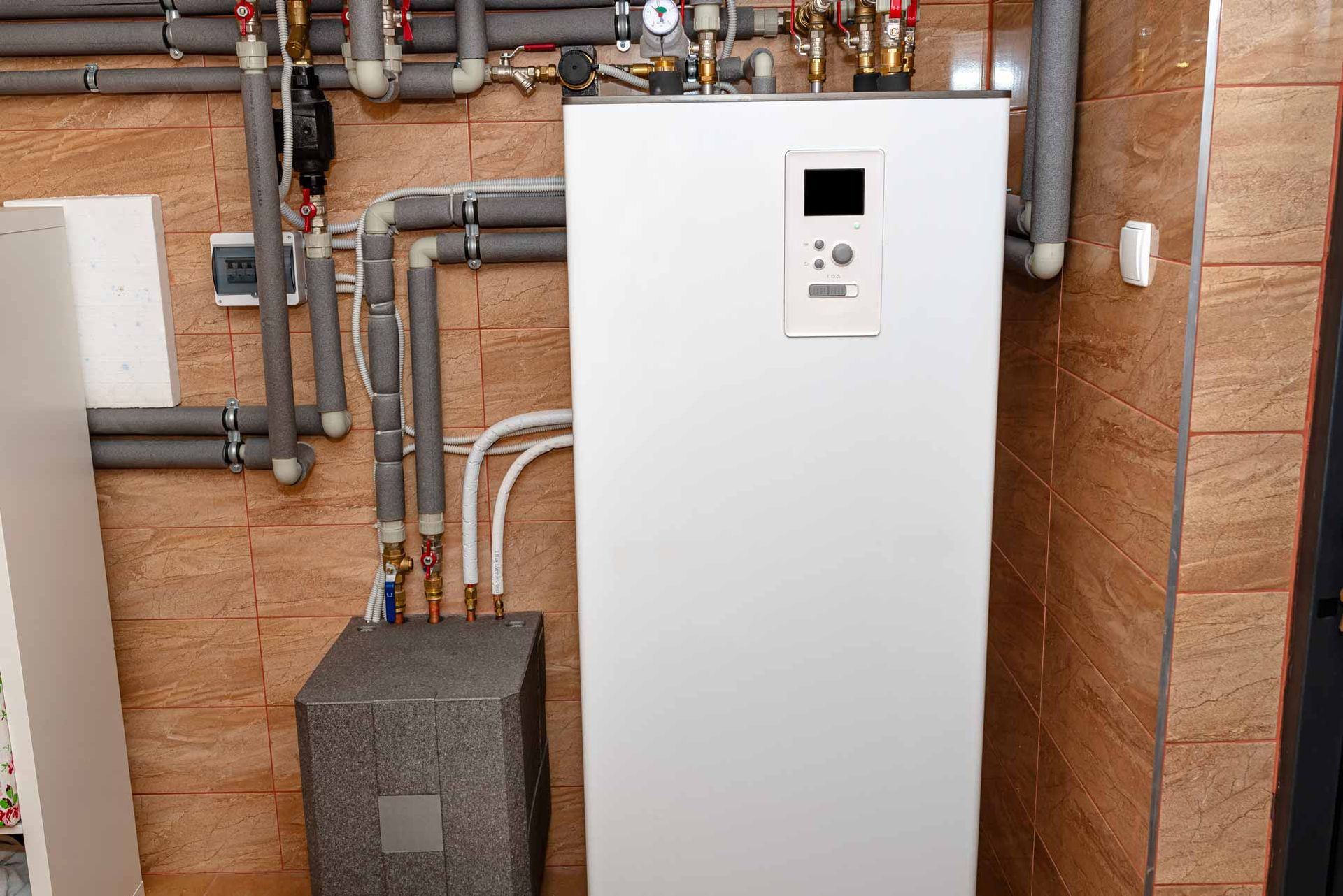 Wall-mounted white boiler in a utility room with exposed pipes and brick walls