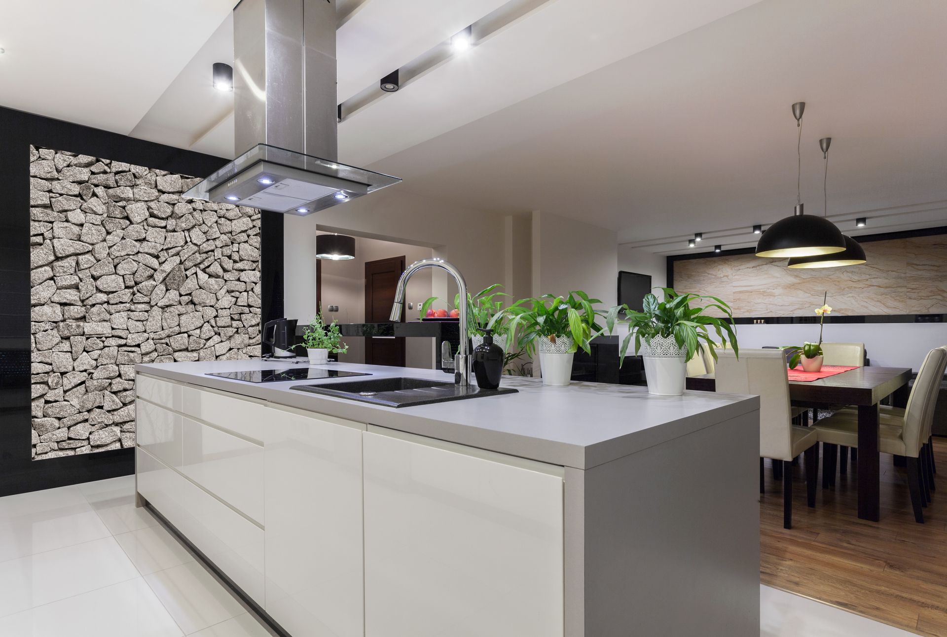Modern kitchen with white island, stainless hood, and dining area in the background