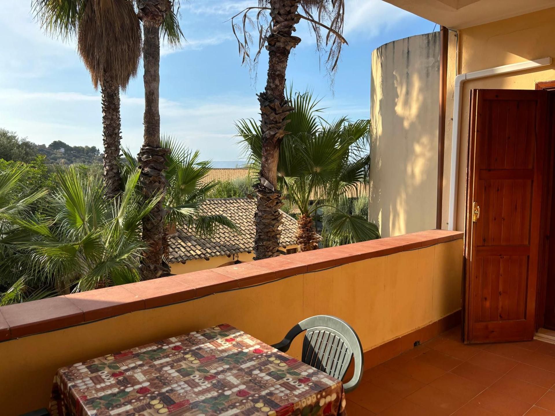 Patio con tavolo e sedie con vista sulle palme e su un paesaggio soleggiato