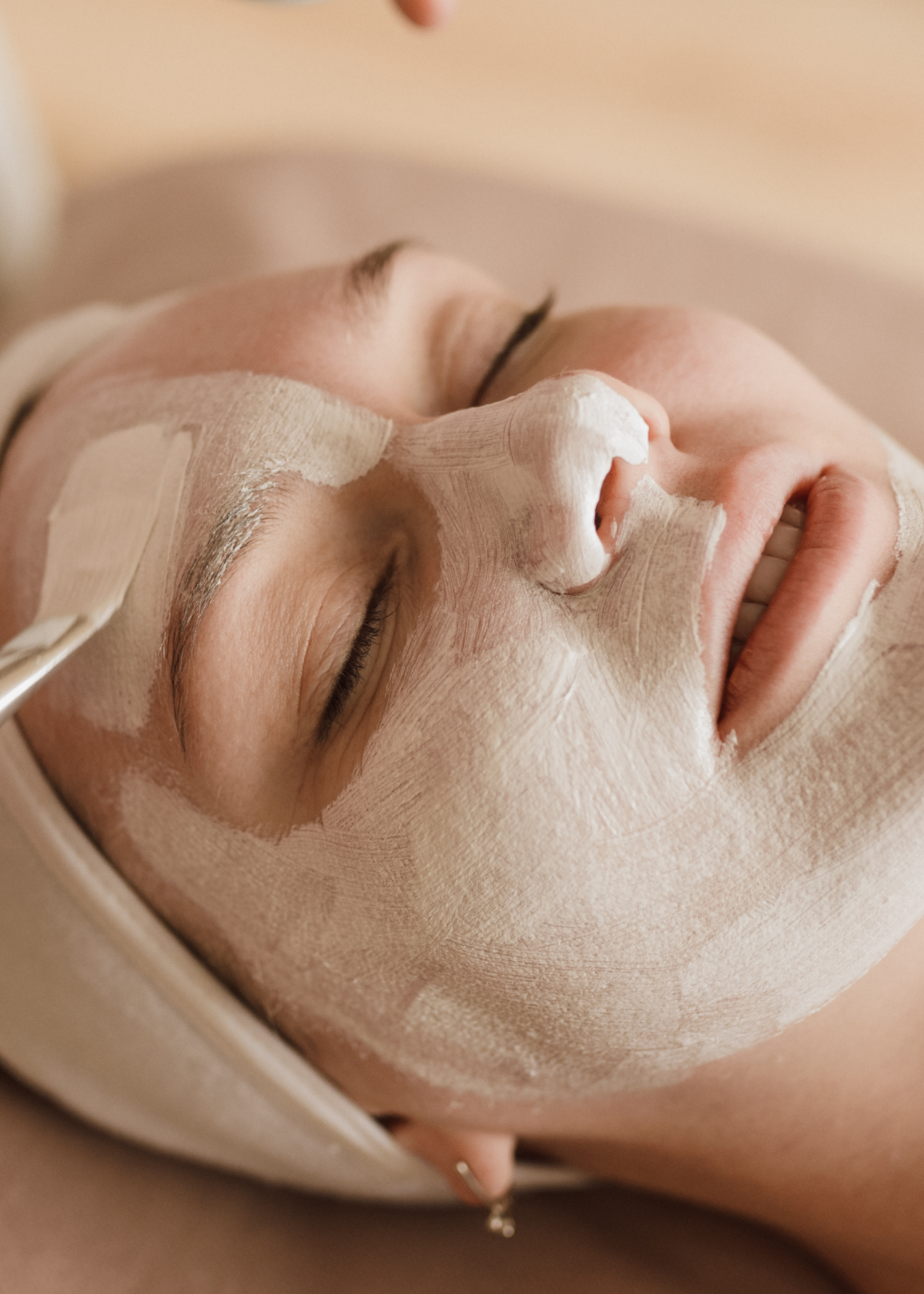 Eine Frau bekommt eine Tonmaske auf ihr Gesicht aufgetragen.