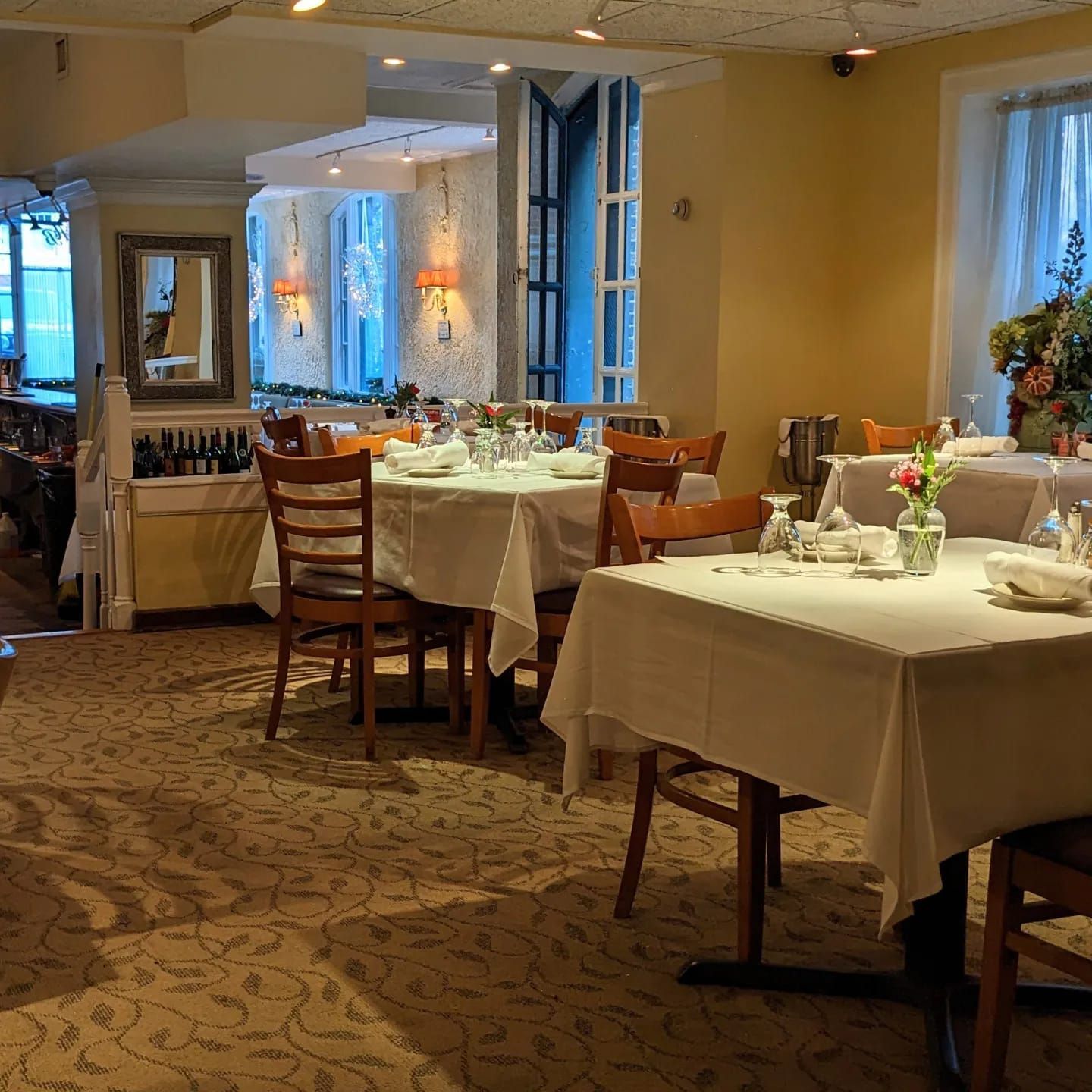Elegant restaurant dining room with set tables, white tablecloths, and warm ambient lighting