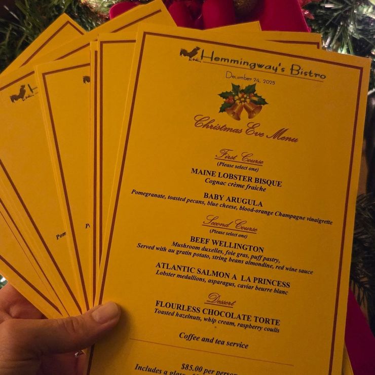 Hand holding a stack of gold wedding invitations with black text and a floral design