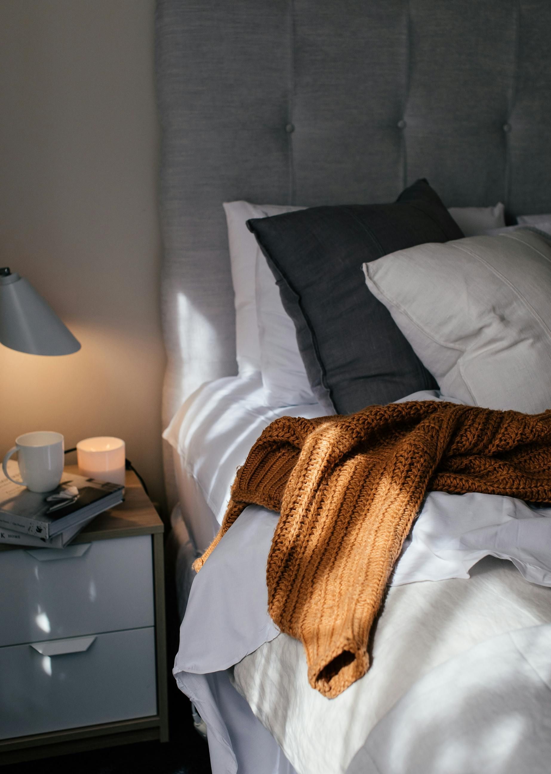 A bed with white sheets and pillows next to a nightstand.