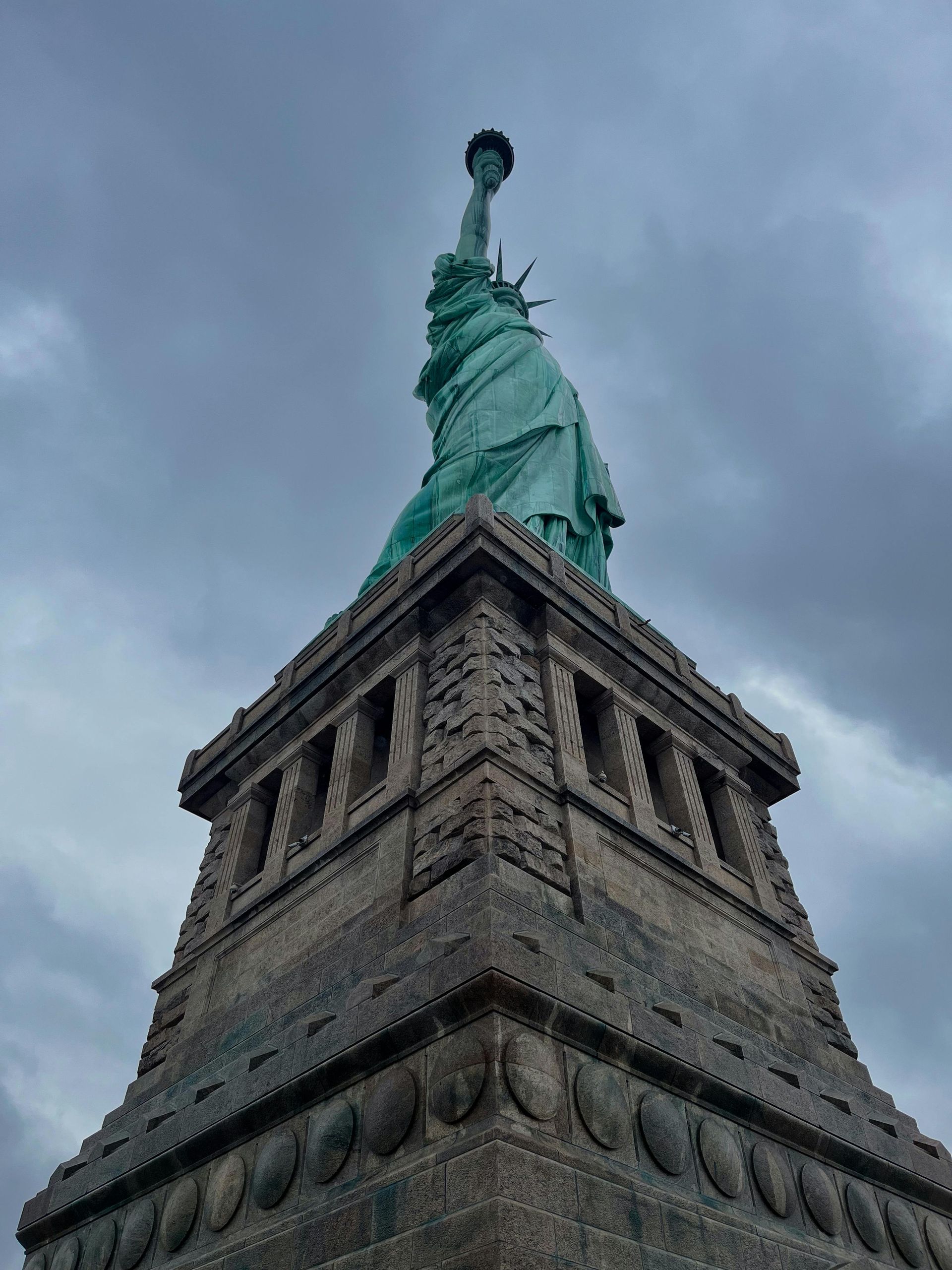 Statue of Liberty stands tall against a cloudy, gray sky.